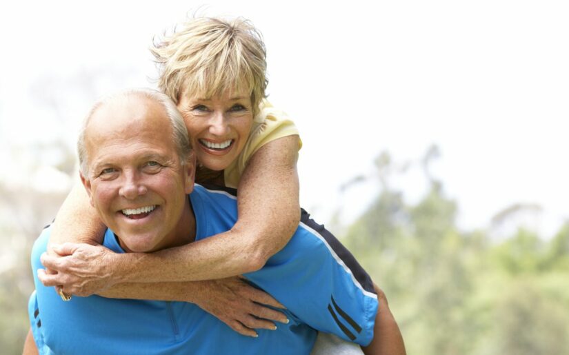 Ehepaar der Generation 60 Plus Reisen - eine Frau freudestrahlend umarmt einen Mann