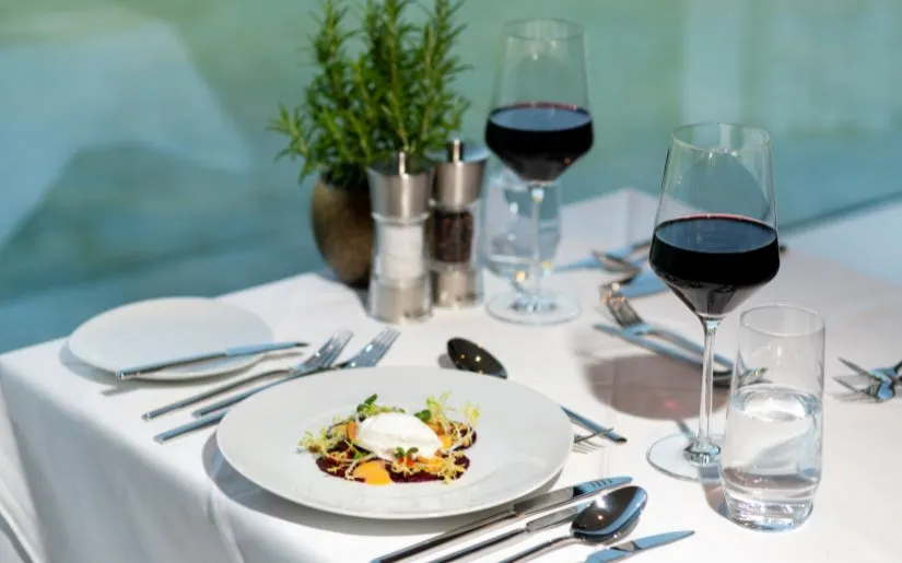 Abendessen als Menügang auf der Thurgau Gold: gefüllter Teller und Gläser mit Rotwein sowie Besteck, Pfeffer und Salz.