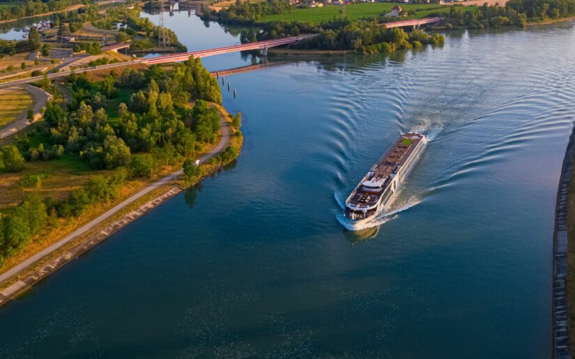 Blick auf ein fahrendes Flusskreuzfahrtschiff aus der Vogelperspektive.